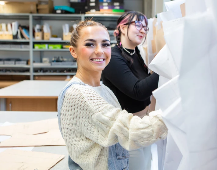 Two fashion students organizing and selecting design patterns in a creative workspace. Two fashion students organizing and selecting design patterns in a creative workspace.